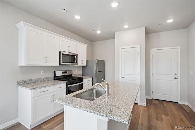 a kitchen with granite countertop cabinets stainless steel appliances a sink and wooden floor