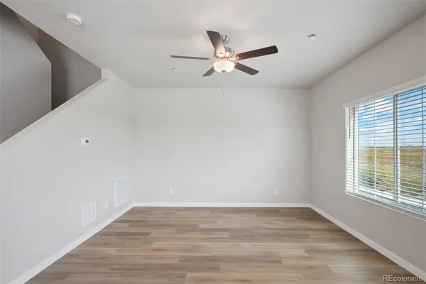 a view of empty room with wooden floor and fan