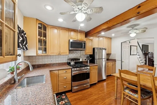 a kitchen with stainless steel appliances granite countertop a stove top oven a sink dishwasher a dining table and chairs with wooden floor