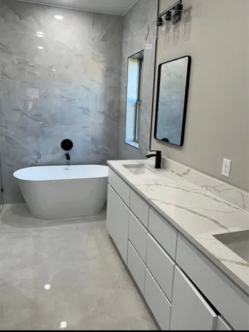a bathroom with a double vanity sink mirror and bathtub