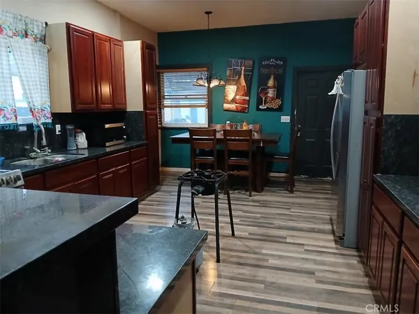 a kitchen with stainless steel appliances kitchen island granite countertop a refrigerator a stove and a sink with wooden floors