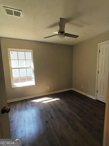 an empty room with wooden floor chandelier and window