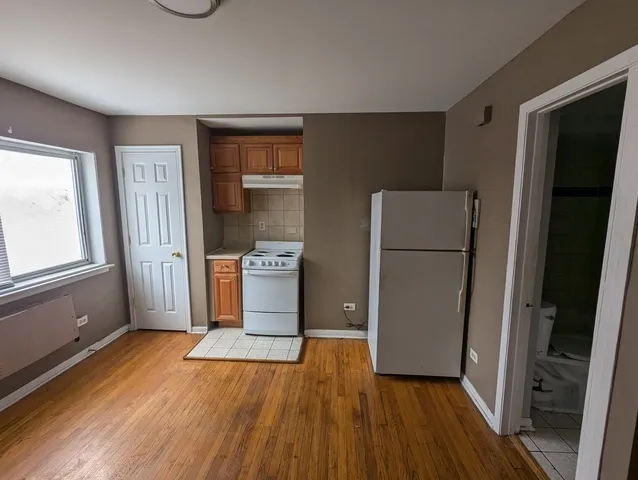 a kitchen with a refrigerator and wooden floor