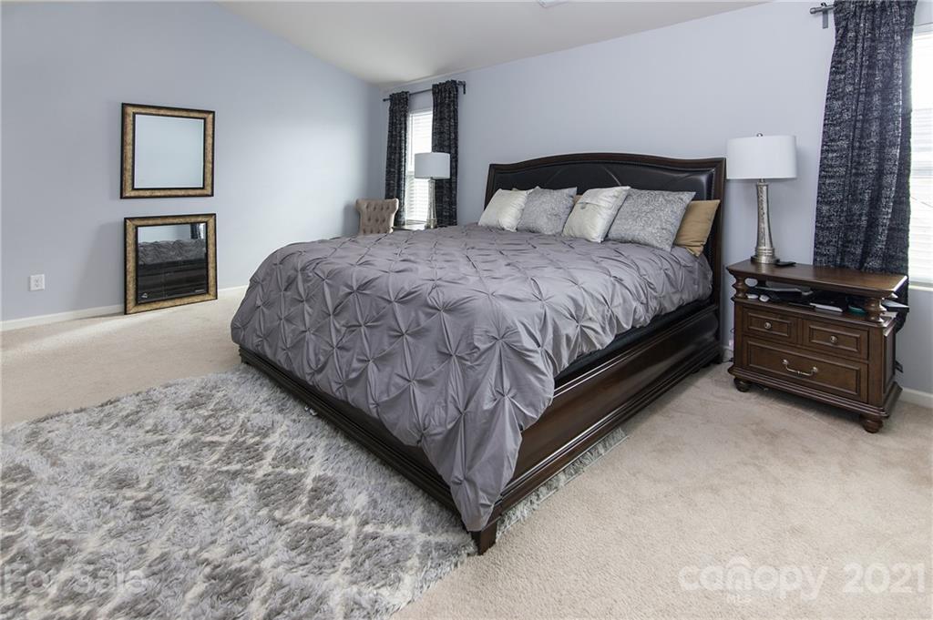 4615 David Cox Road Charlotte, NC 28269 - Photo 14 of 20 a large bed sitting in a bedroom next to a window with tv
