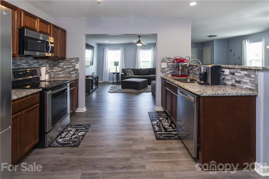 4615 David Cox Road Charlotte, NC 28269 - Photo 7 of 20 a kitchen with granite countertop a stove top oven a sink dishwasher a dining table and chairs with wooden floor