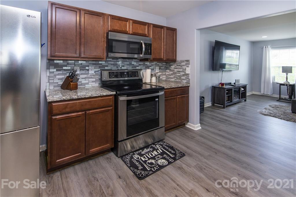 4615 David Cox Road Charlotte, NC 28269 - Photo 8 of 20 a kitchen with stainless steel appliances granite countertop a stove top oven a sink dishwasher a refrigerator and a microwave
