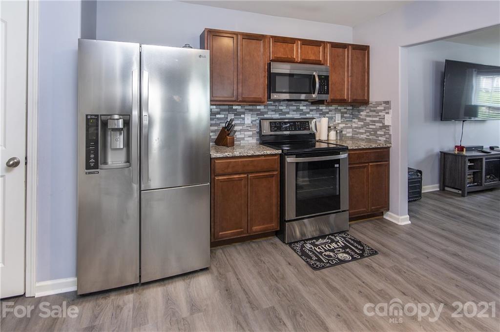 4615 David Cox Road Charlotte, NC 28269 - Photo 9 of 20 a kitchen with granite countertop a refrigerator stove and microwave