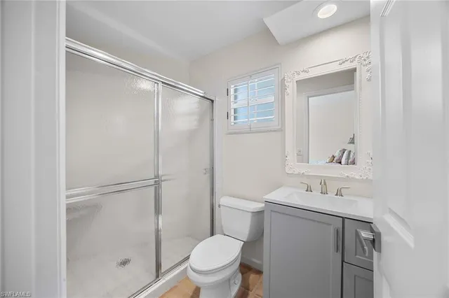 a bathroom with a shower sink vanity mirror and toilet