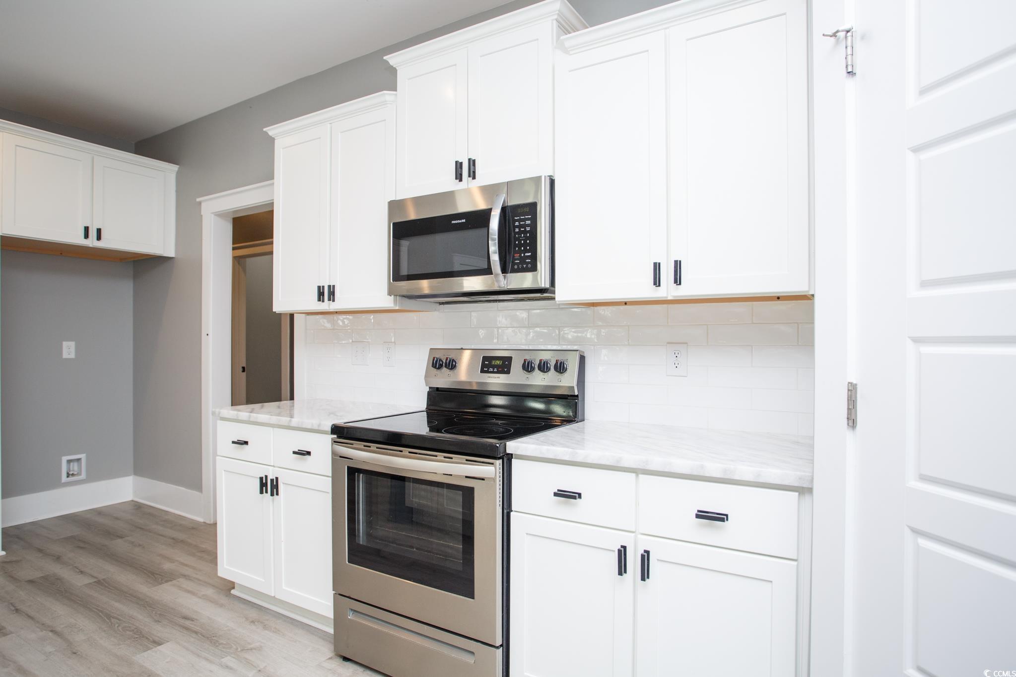 261 Marsh Tacky Loop Myrtle Beach, SC 29588 - Photo 12 of 40 Kitchen featuring white cabinetry, stainless steel appliances, light stone countertops, and decorative backsplash