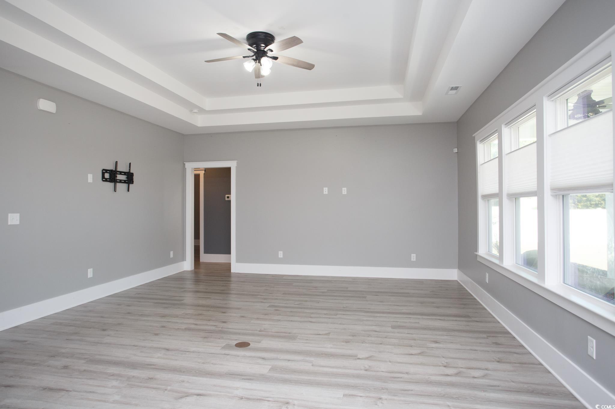 261 Marsh Tacky Loop Myrtle Beach, SC 29588 - Photo 15 of 40 Empty room featuring ceiling fan, light hardwood / wood-style floors, and a tray ceiling