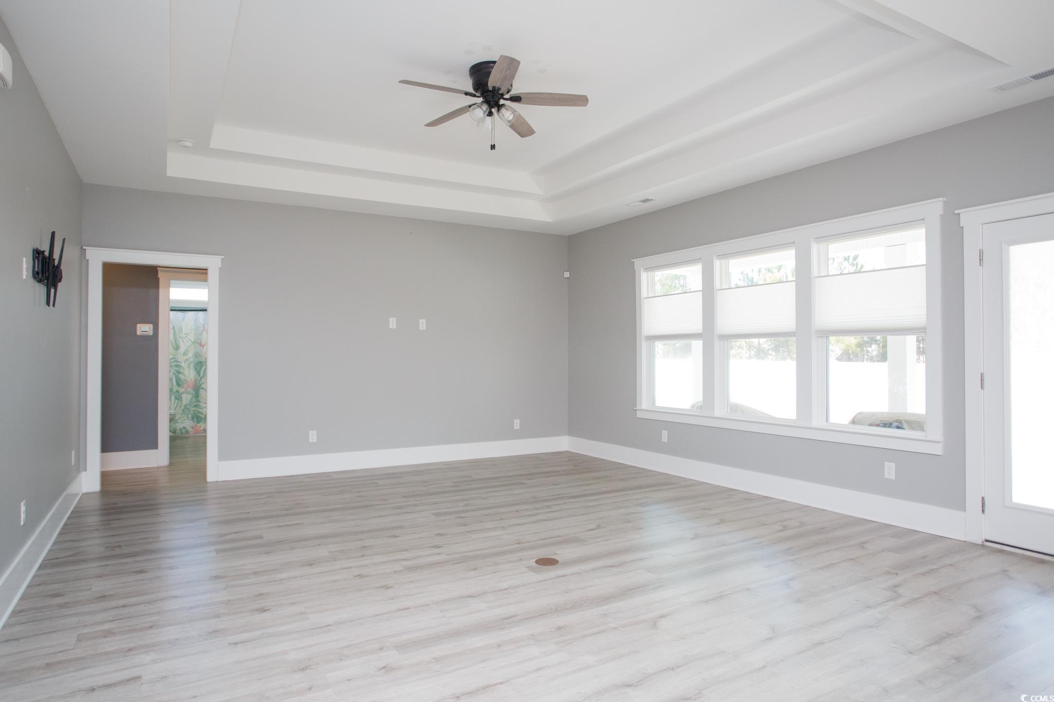 261 Marsh Tacky Loop Myrtle Beach, SC 29588 - Photo 16 of 40 Unfurnished room with ceiling fan, a raised ceiling, and light hardwood / wood-style flooring