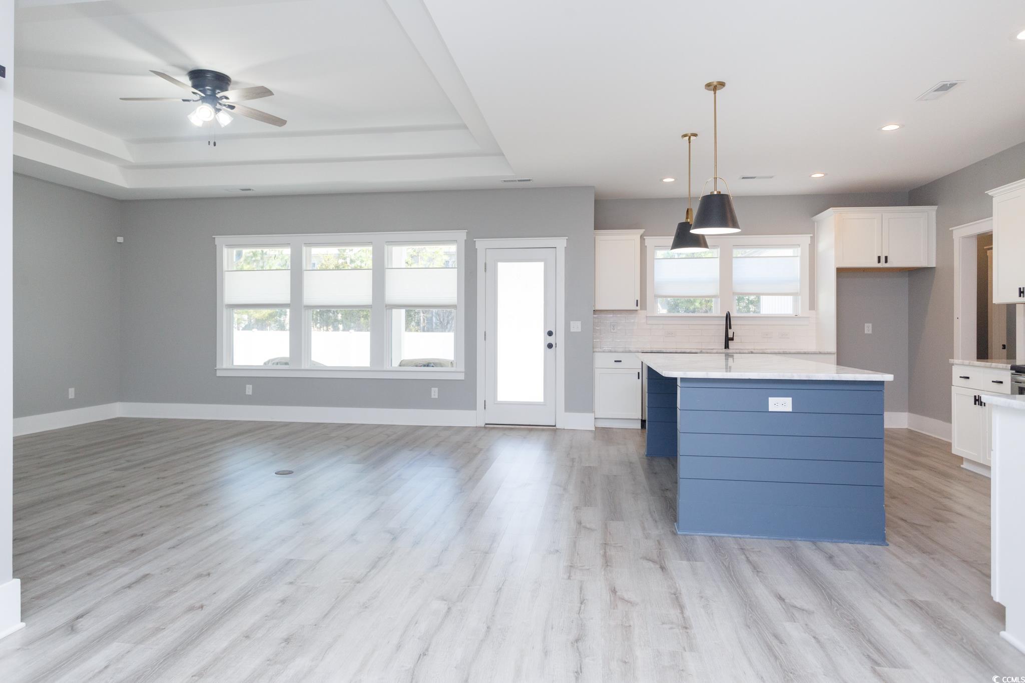 261 Marsh Tacky Loop Myrtle Beach, SC 29588 - Photo 7 of 40 Kitchen featuring a tray ceiling, a center island, hanging light fixtures, and white cabinets