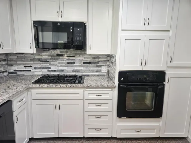 a kitchen with granite countertop white cabinets and stainless steel appliances