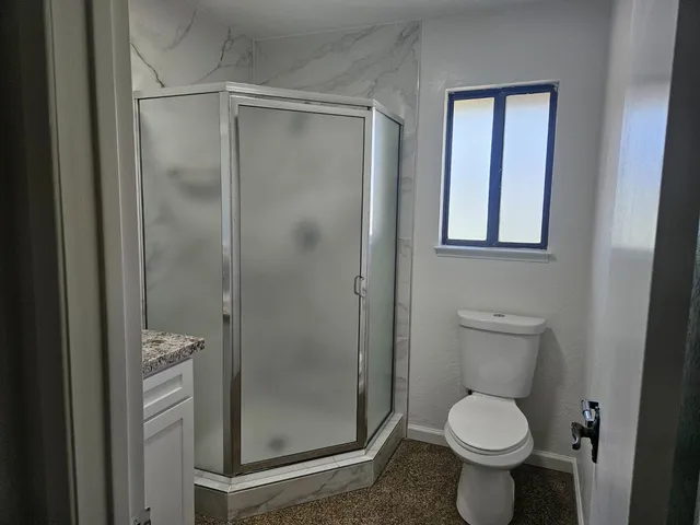 a bathroom with a granite countertop toilet a sink and a mirror