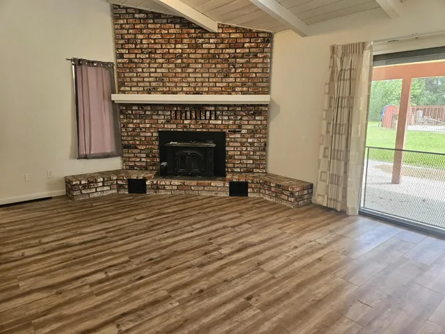 a view of empty room with wooden floor and fireplace