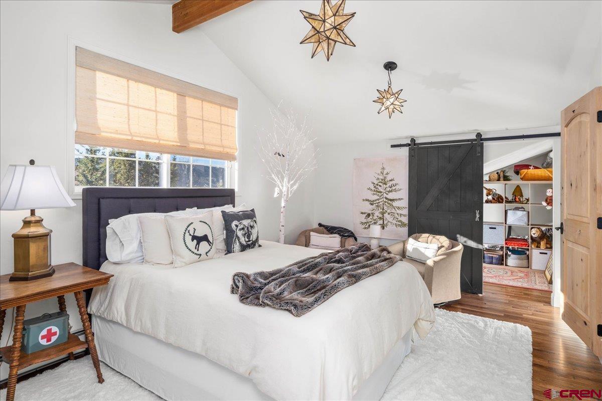 240 Vista Drive Ridgway, CO 81432 - Photo 26 of 41 a bedroom with a bed and a chandelier