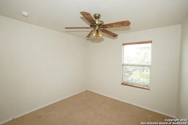 an empty room with a window and a fan