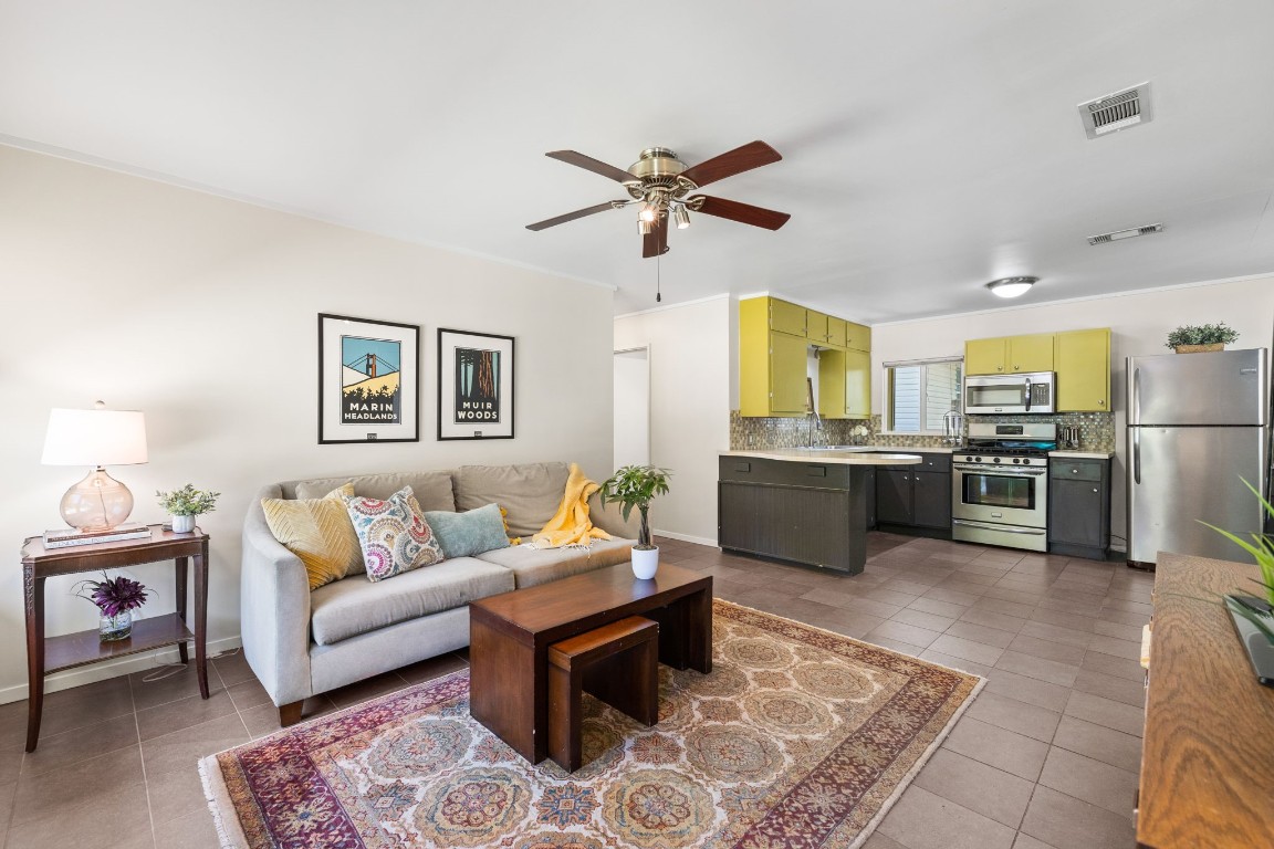 a living room with furniture kitchen view and a chandelier