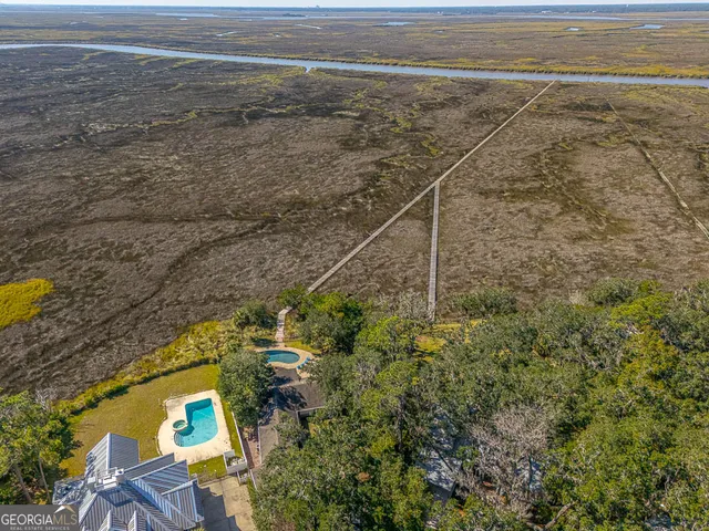 a view of a house with a small yard plants and large trees