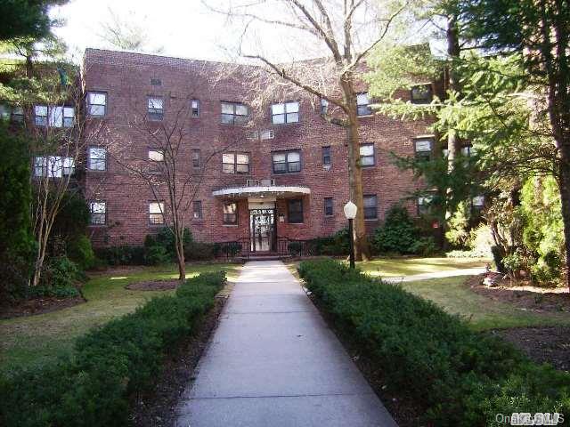 50 Brompton Road, Unit 1K Great Neck, NY 11021 - Photo 1 of 1 a view of a brick building next to a yard