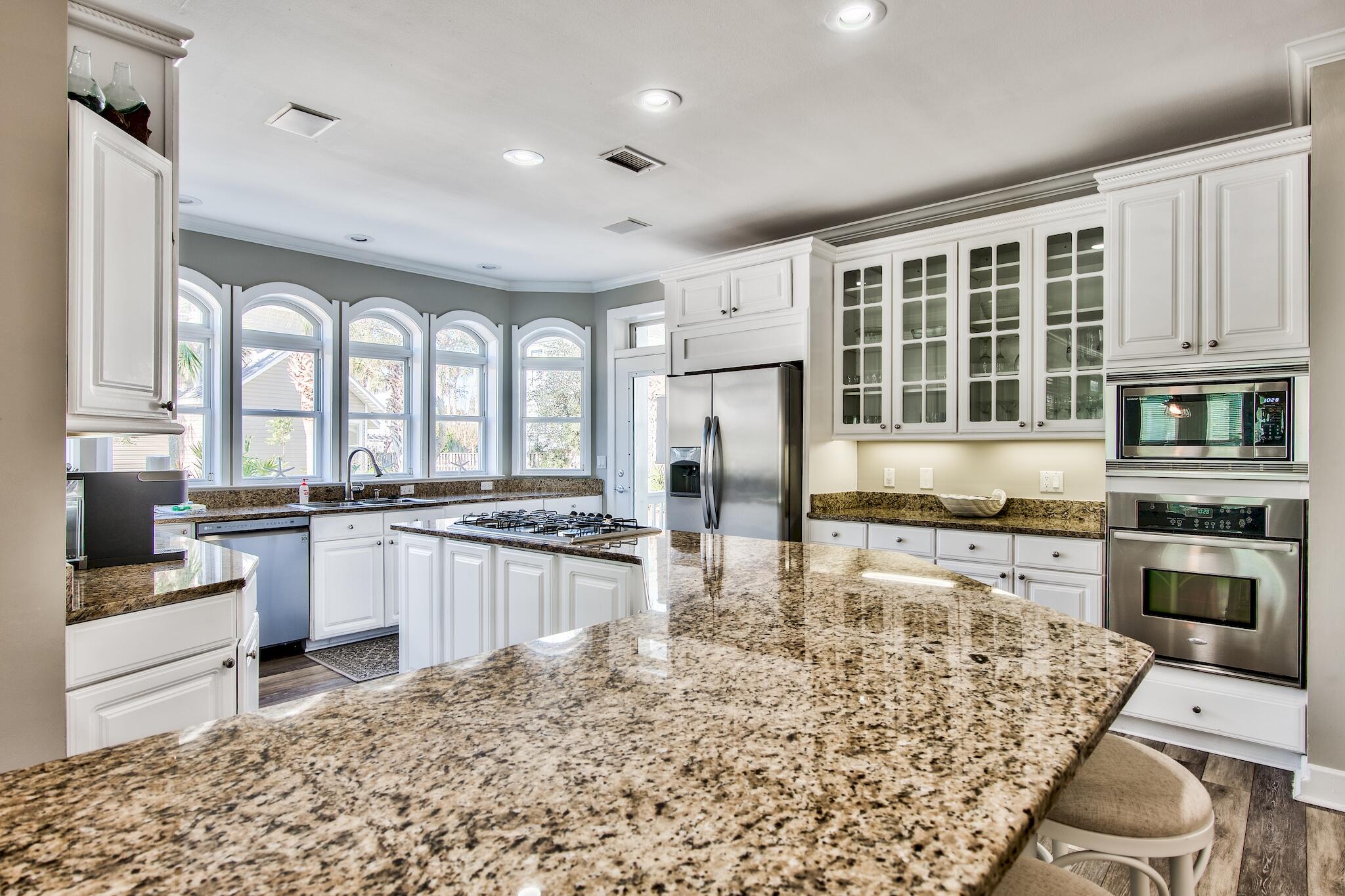 4489 Ocean View Drive Destin, FL 32541 - Photo 10 of 61 a kitchen with stainless steel appliances granite countertop a stove top oven a sink dishwasher a dining table and chairs with wooden floor