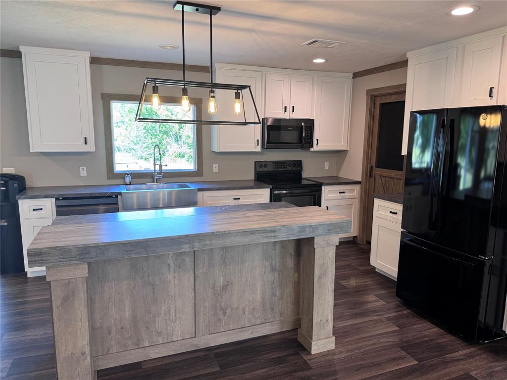7268 Brangus Road Anna, TX 75409 - Photo 8 of 21 Kitchen featuring a wood-finish island with seating, dark wood-finish flooring, white cabinetry, dark countertops, and a stainless steel sink with a gooseneck faucet