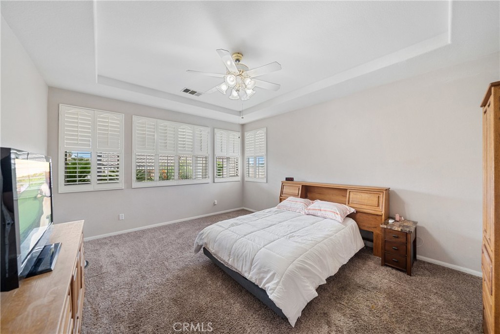 28713 Raintree Drive Menifee, CA 92584 - Photo 19 of 56 a bedroom with a large bed and a flat tv screen on dresser