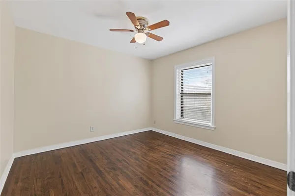 an empty room with wooden floor and ceiling fan