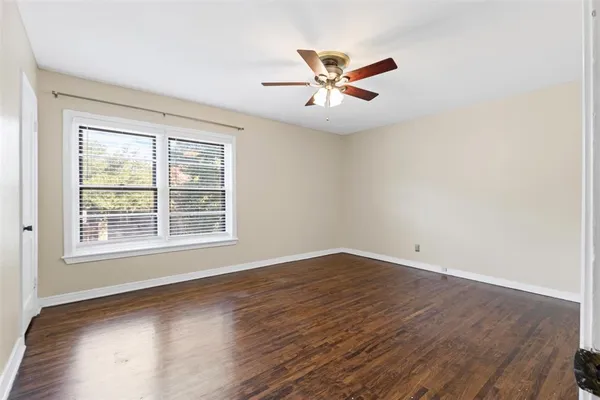 an empty room with wooden floor fan and windows