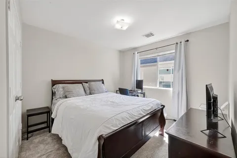 a bedroom with a bed and a flat tv screen on the dresser