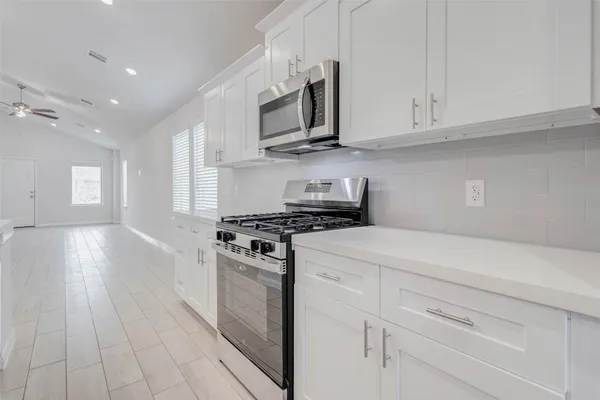 a kitchen with stainless steel appliances granite countertop a stove a sink and white cabinets