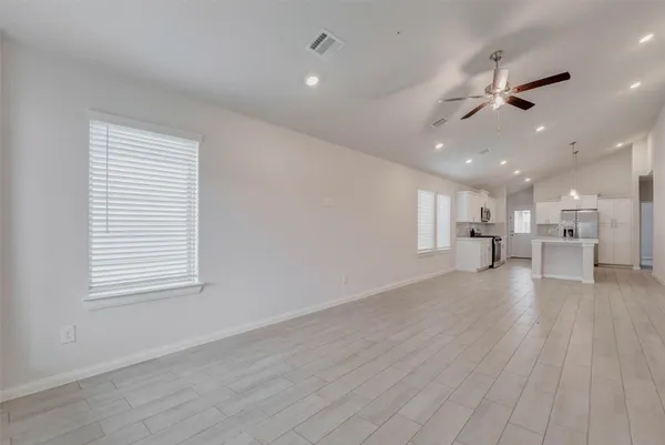 an empty room with wooden floor an entryway and windows