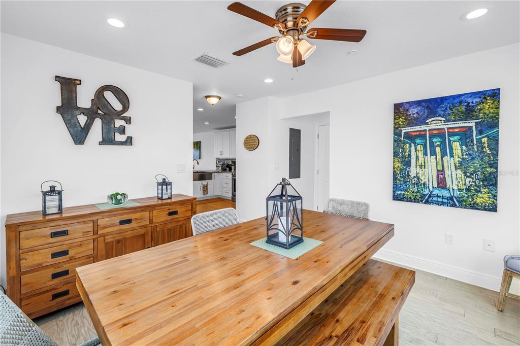 100 Windrush Boulevard, Unit 1 Indian Rocks Beach, FL 33785 - Photo 11 of 37 a dining room with wooden floor a chandelier fan a wooden table and chairs