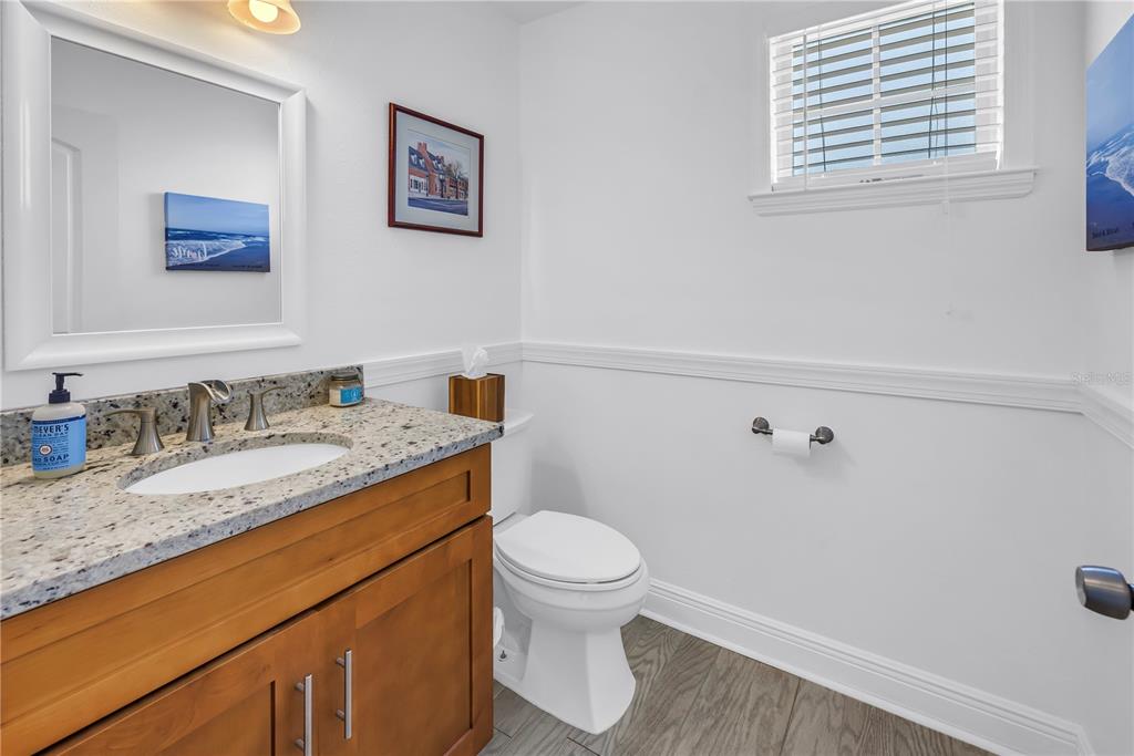 100 Windrush Boulevard, Unit 1 Indian Rocks Beach, FL 33785 - Photo 13 of 37 a bathroom with a granite countertop sink mirror vanity and toilet