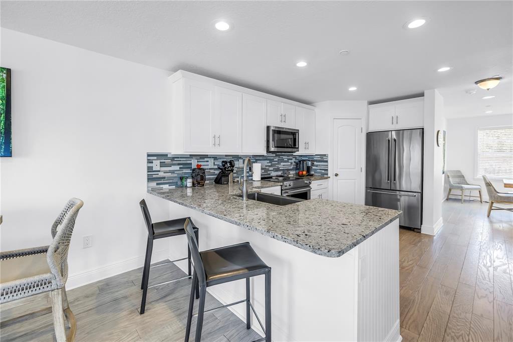100 Windrush Boulevard, Unit 1 Indian Rocks Beach, FL 33785 - Photo 9 of 37 a kitchen with kitchen island a refrigerator stove microwave and cabinets