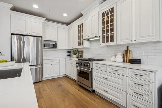 a kitchen with cabinets stainless steel appliances and wooden floor