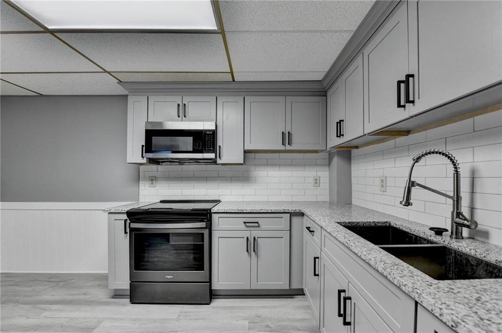 2377 Centerville Rosebud Road Loganville, GA 30052 - Photo 53 of 76 a kitchen with granite countertop white cabinets and stainless steel appliances