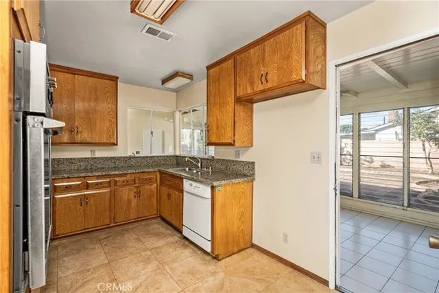 a large kitchen with granite countertop a sink and dishwasher a stove top oven with wooden floor