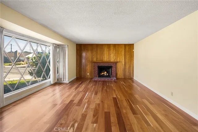 a view of empty room with wooden floor and fireplace