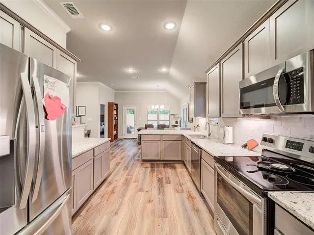 a large kitchen with stainless steel appliances lots of counter space and wooden floor