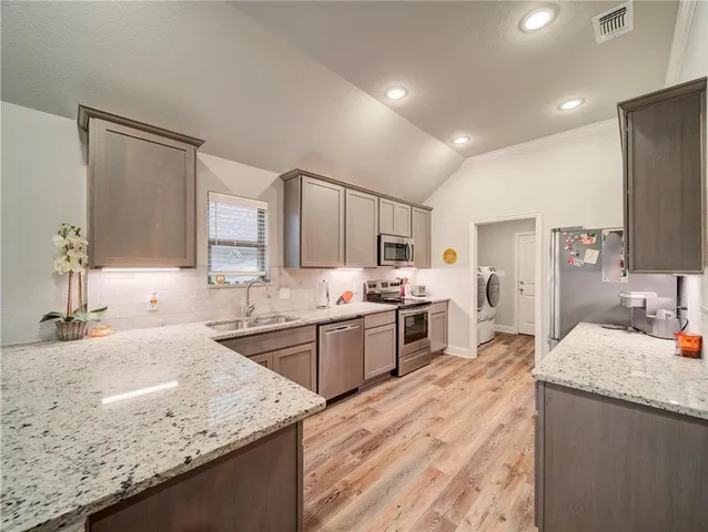 a large kitchen with granite countertop a sink counter top space appliances and cabinets