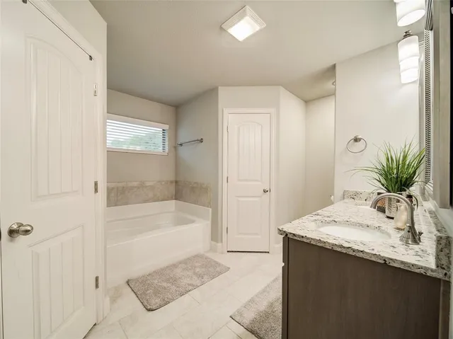 a bathroom with a tub sink and mirror