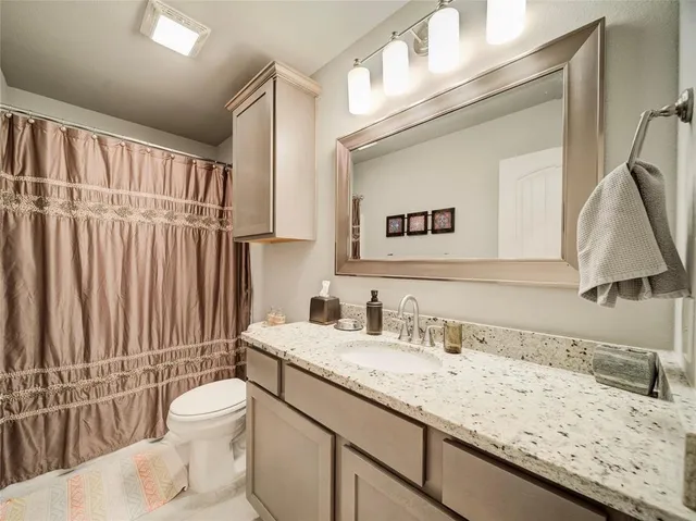 a bathroom with a granite countertop sink a toilet and a mirror