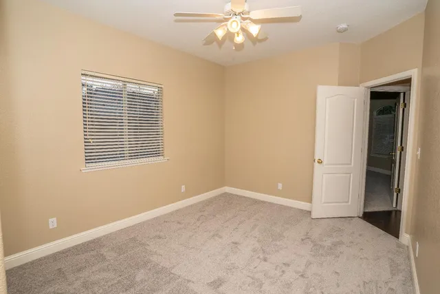 an empty room with windows and fan