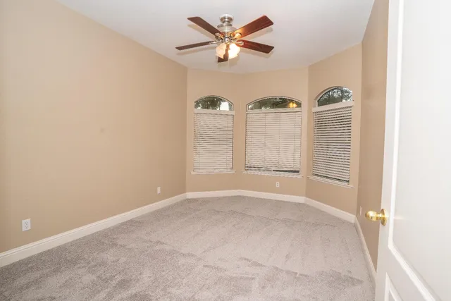 an empty room with windows and ceiling fan
