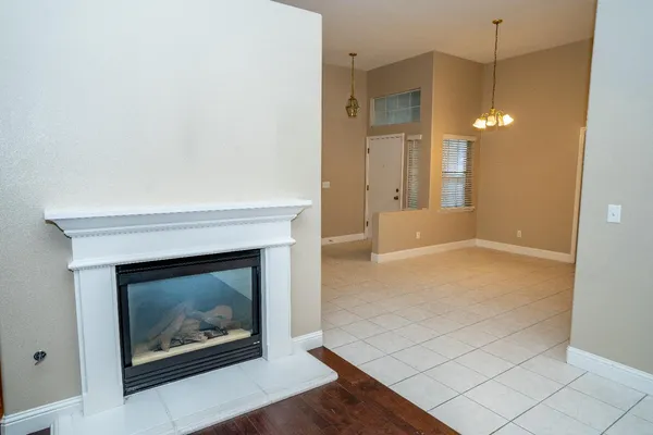 a view of an empty room with wooden floor and a fireplace