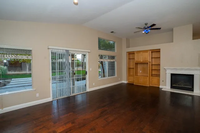 a view of wooden floor fire place and windows in an empty room