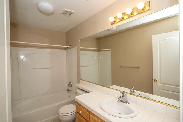 a bathroom with a granite countertop sink toilet a mirror and shower