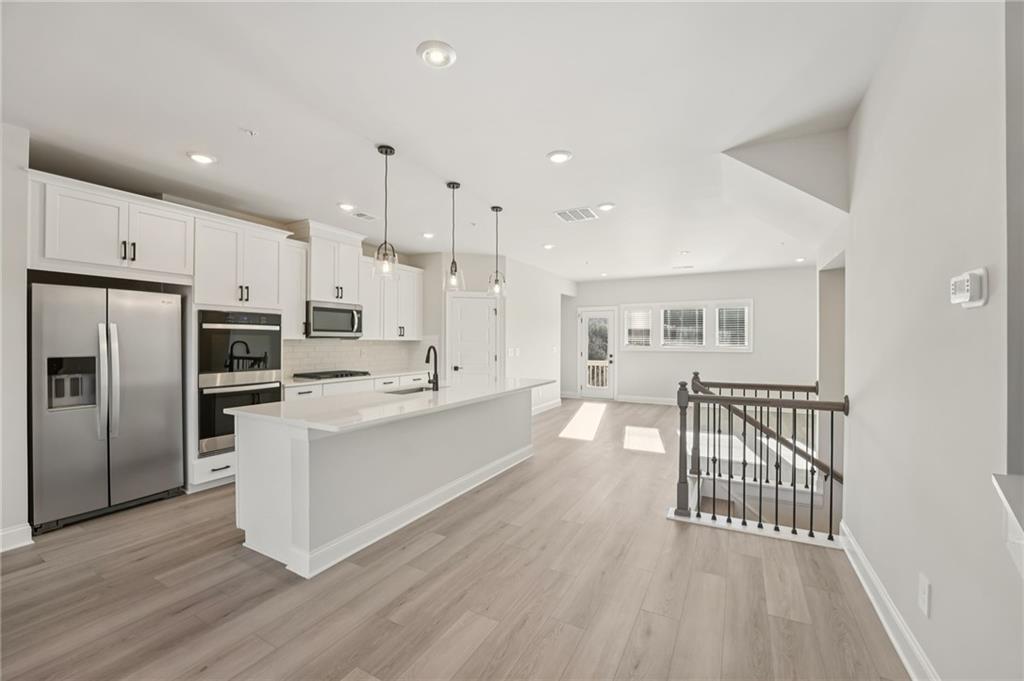 6440 Pinin Place Cumming, GA 30041 - Photo 25 of 52 a large kitchen with a center island wooden floor stainless steel appliances and windows