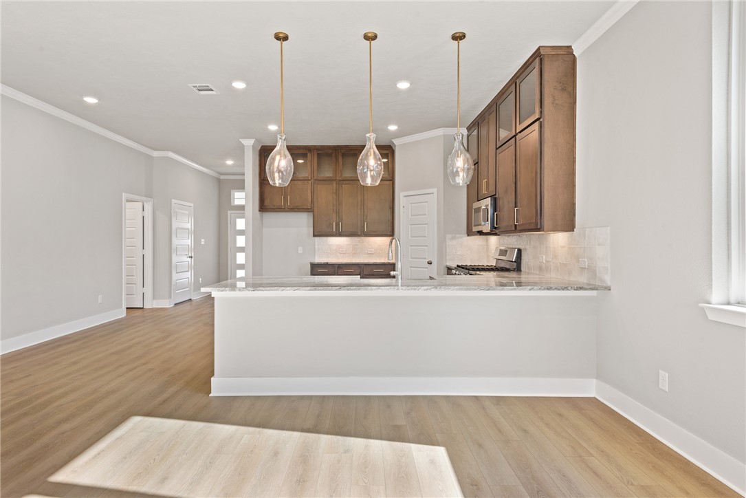 4245 Appalachian Trail Bryan, TX 77802 - Photo 14 of 30 a view of a kitchen with kitchen island a sink wooden floor and a chandelier